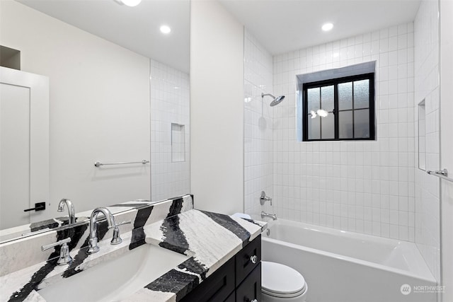 full bathroom featuring vanity, tiled shower / bath, and toilet