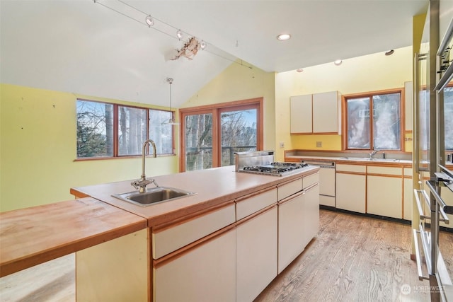 kitchen featuring pendant lighting, sink, lofted ceiling, dishwasher, and white cabinetry