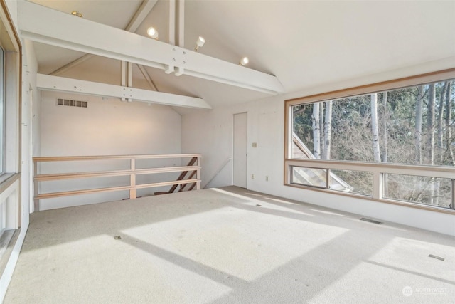 spare room with a healthy amount of sunlight, carpet, and vaulted ceiling with beams