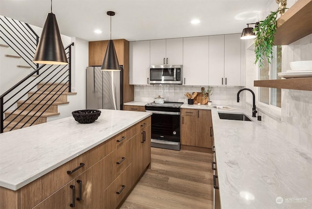 kitchen featuring pendant lighting, sink, white cabinets, and appliances with stainless steel finishes