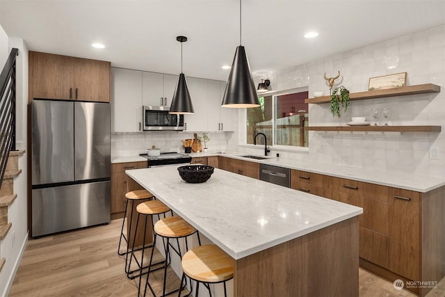 kitchen featuring pendant lighting, sink, appliances with stainless steel finishes, backsplash, and a center island