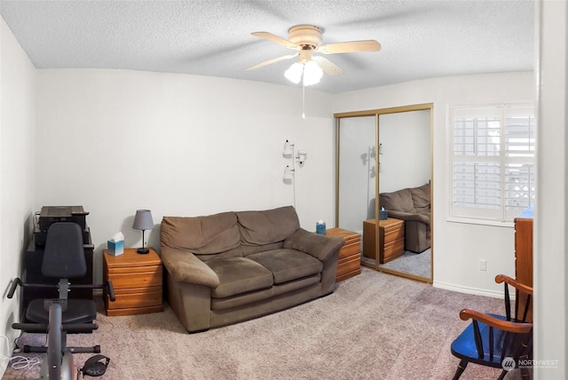 carpeted living room with ceiling fan and a textured ceiling