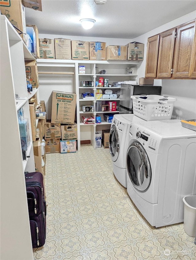 washroom with cabinets, washer and dryer, and a textured ceiling