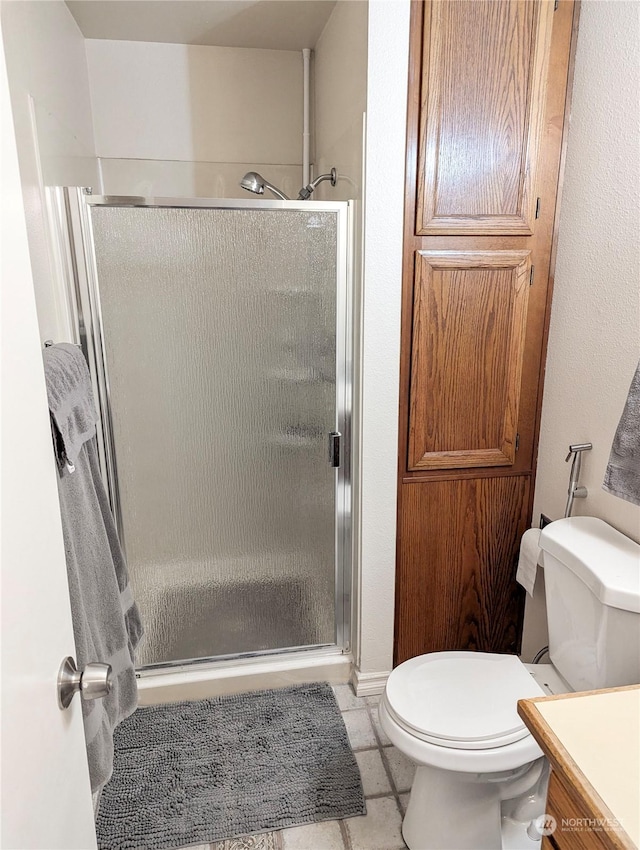 bathroom with an enclosed shower, vanity, tile patterned flooring, and toilet