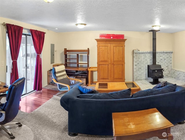 living room with a wood stove, electric panel, a textured ceiling, and carpet flooring