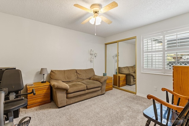 living room featuring a ceiling fan, a textured ceiling, and carpet flooring
