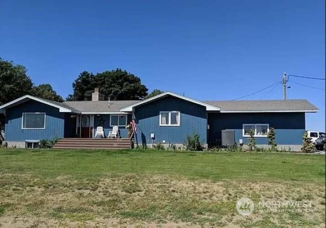 rear view of property featuring a yard and central AC unit