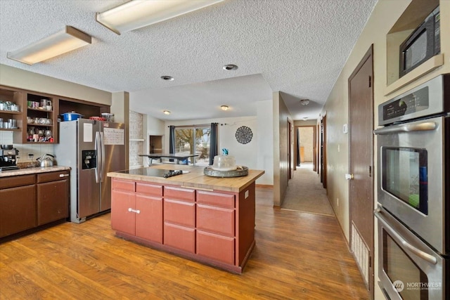 kitchen featuring stainless steel appliances, a kitchen island, butcher block countertops, and light hardwood / wood-style floors