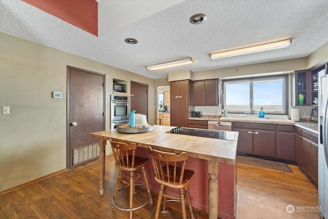 kitchen featuring butcher block counters, hardwood / wood-style floors, a kitchen island, and appliances with stainless steel finishes