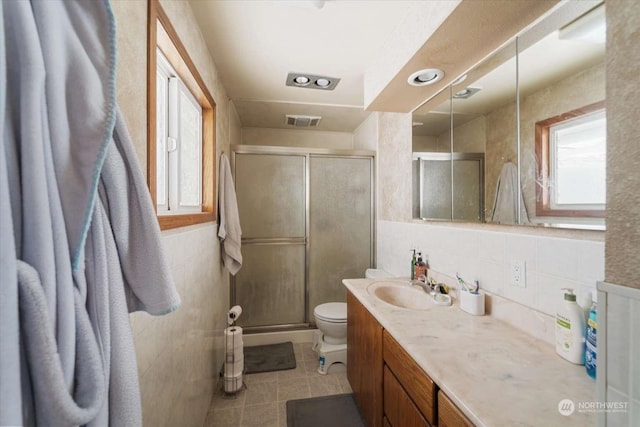 bathroom featuring tasteful backsplash, tile patterned flooring, vanity, walk in shower, and toilet