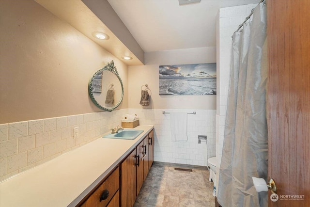 bathroom with vanity, tile walls, and toilet