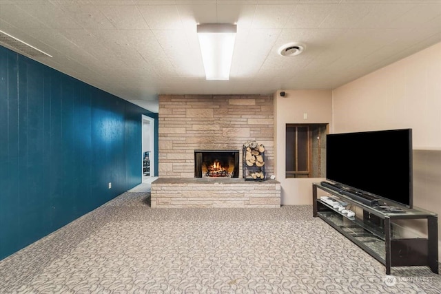 living room with a stone fireplace and carpet flooring