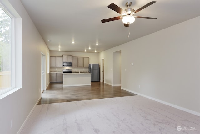 kitchen featuring carpet flooring, a kitchen island, ceiling fan, and appliances with stainless steel finishes