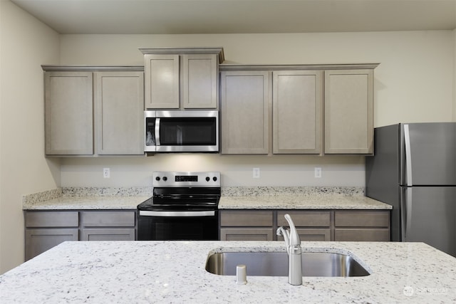 kitchen with sink, light stone countertops, and appliances with stainless steel finishes