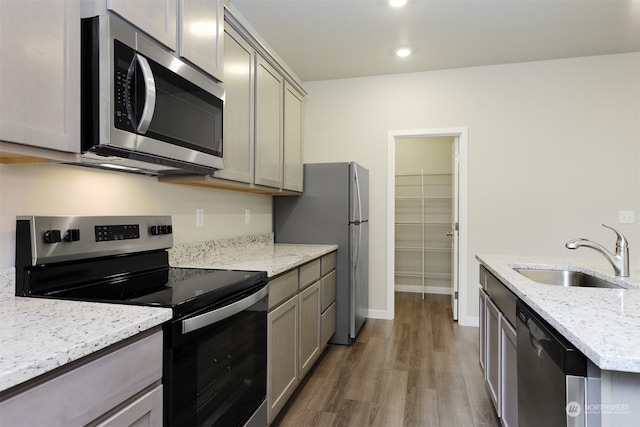 kitchen with sink, gray cabinets, appliances with stainless steel finishes, light stone counters, and dark hardwood / wood-style flooring