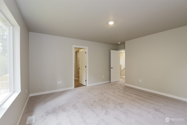 unfurnished bedroom featuring light carpet and connected bathroom