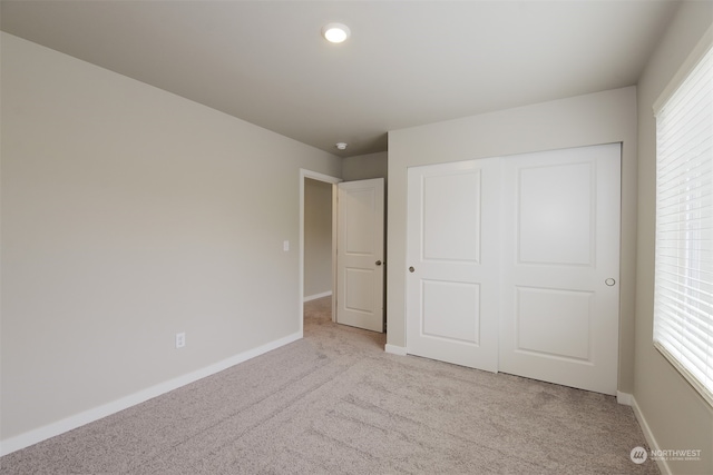 unfurnished bedroom with light carpet and a closet