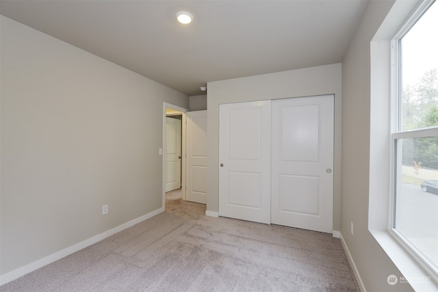 unfurnished bedroom with light colored carpet and a closet