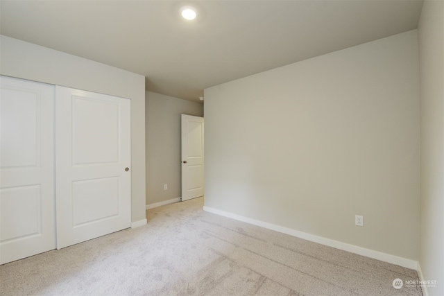 unfurnished bedroom featuring a closet and light carpet