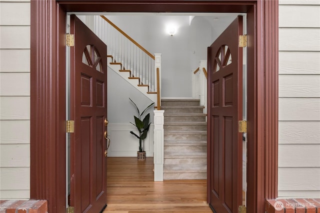 entrance foyer featuring light wood-style floors, wainscoting, and stairs