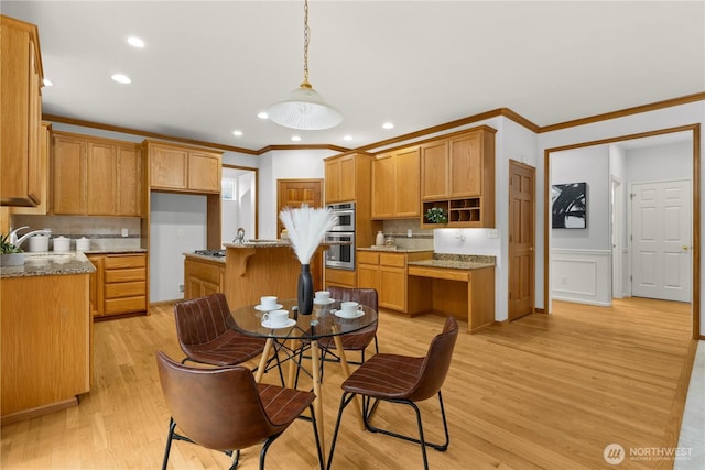 kitchen with light wood finished floors, a kitchen island, pendant lighting, stainless steel double oven, and light stone countertops