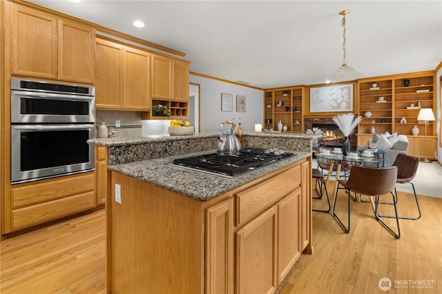 kitchen featuring stainless steel appliances, a kitchen island, dark stone countertops, and a lit fireplace