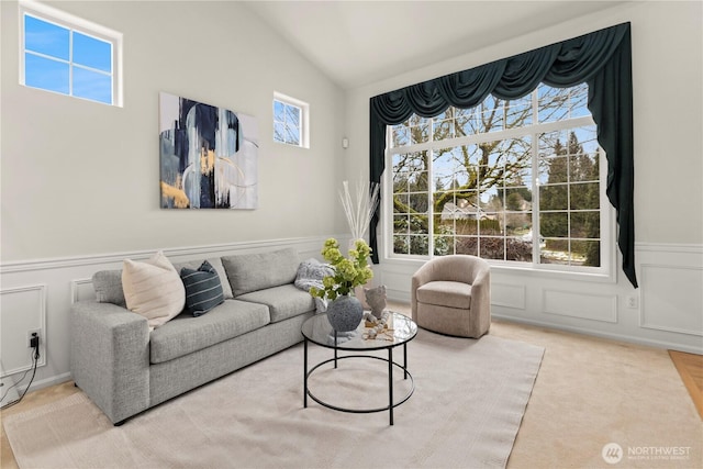 living area with a decorative wall, carpet floors, a wainscoted wall, and vaulted ceiling