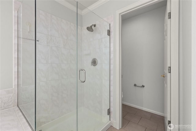 bathroom featuring a stall shower, baseboards, tile patterned floors, and crown molding