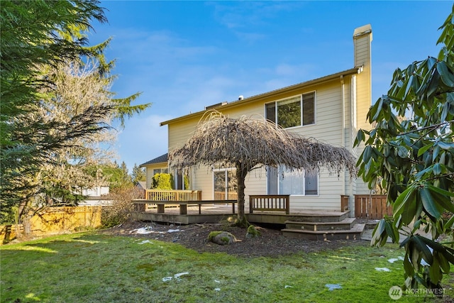 rear view of property with a deck, fence, a yard, and a chimney