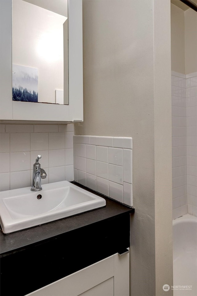 bathroom featuring vanity, a bath, and backsplash