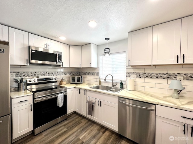 kitchen with stainless steel appliances, decorative light fixtures, sink, and white cabinets