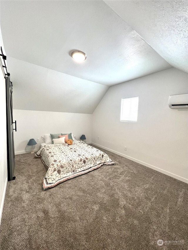 bedroom featuring a barn door, a wall mounted AC, carpet, and a textured ceiling