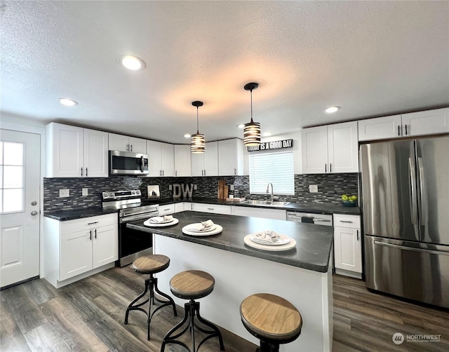 kitchen with a kitchen bar, stainless steel appliances, white cabinets, and a kitchen island