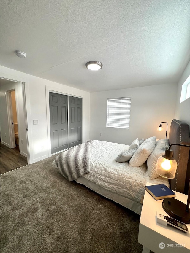 bedroom with a textured ceiling, dark carpet, and a closet