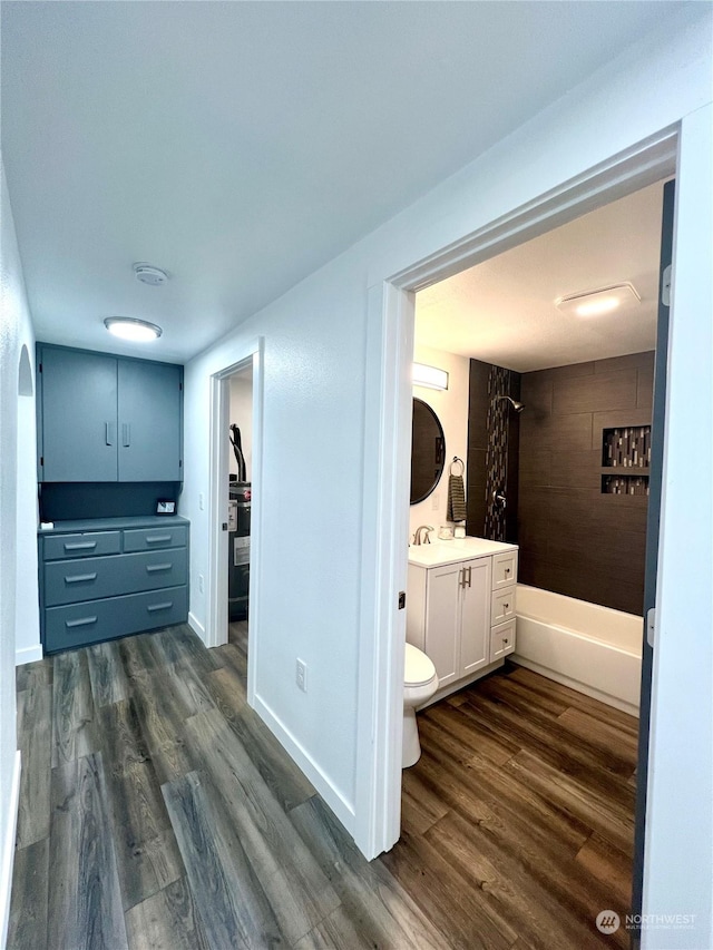 full bathroom featuring hardwood / wood-style flooring, tiled shower / bath, vanity, and toilet