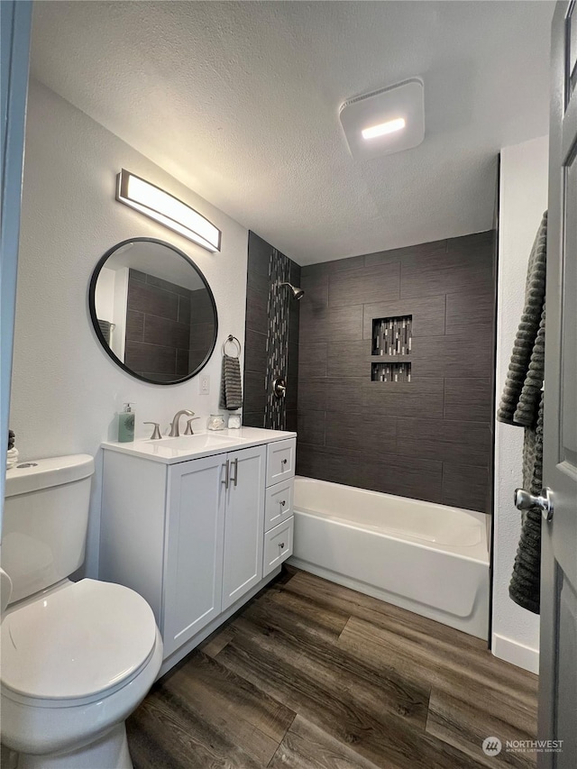 full bathroom featuring toilet, tiled shower / bath, a textured ceiling, vanity, and hardwood / wood-style floors