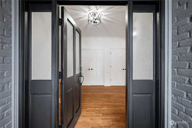 corridor with hardwood / wood-style flooring and brick wall