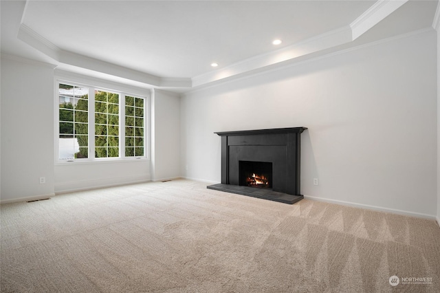 unfurnished living room with a raised ceiling, crown molding, light carpet, and a high end fireplace