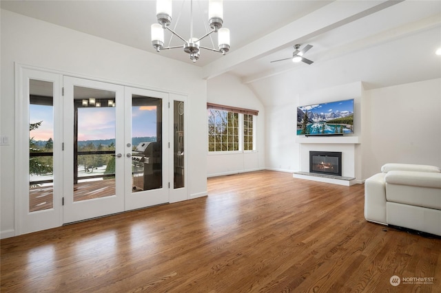 unfurnished living room featuring wood-type flooring, vaulted ceiling with beams, a notable chandelier, and french doors