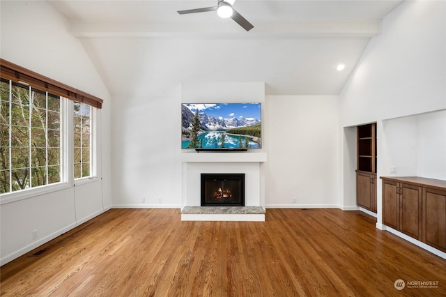 unfurnished living room with beamed ceiling, ceiling fan, high vaulted ceiling, and light hardwood / wood-style flooring