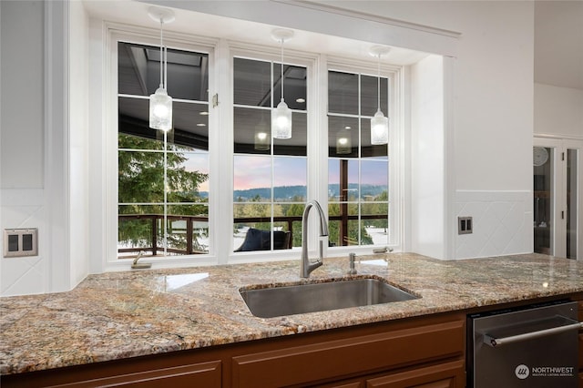 kitchen featuring dishwasher, sink, and light stone counters