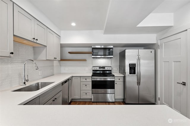 kitchen with gray cabinetry, sink, decorative backsplash, and stainless steel appliances