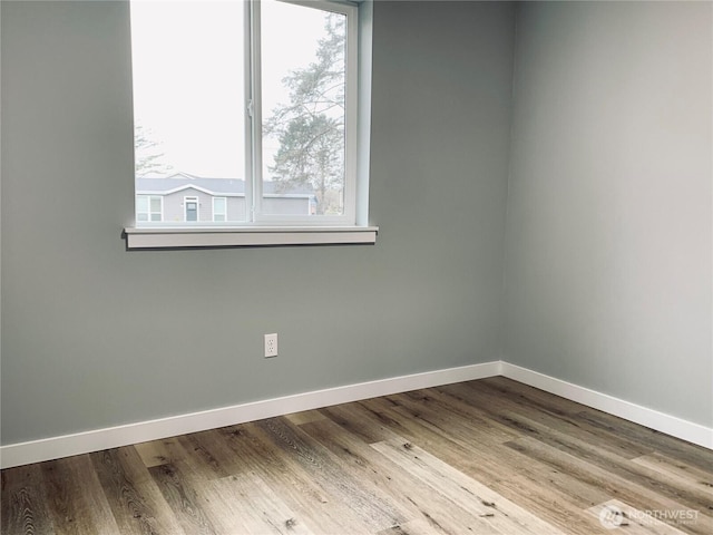 unfurnished room featuring light wood-style flooring, a wealth of natural light, and baseboards