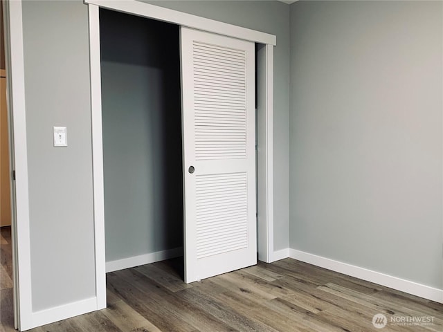 unfurnished bedroom featuring baseboards, a closet, and wood finished floors