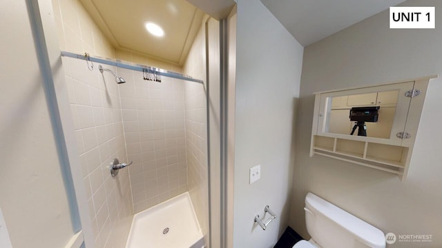 bathroom featuring tiled shower and toilet