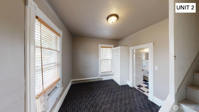 interior space with baseboard heating, ornamental molding, and a wall unit AC