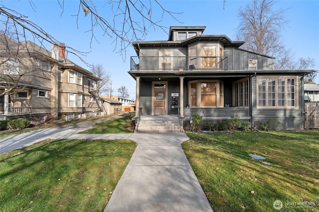 view of front of house featuring a porch, a balcony, and a front lawn