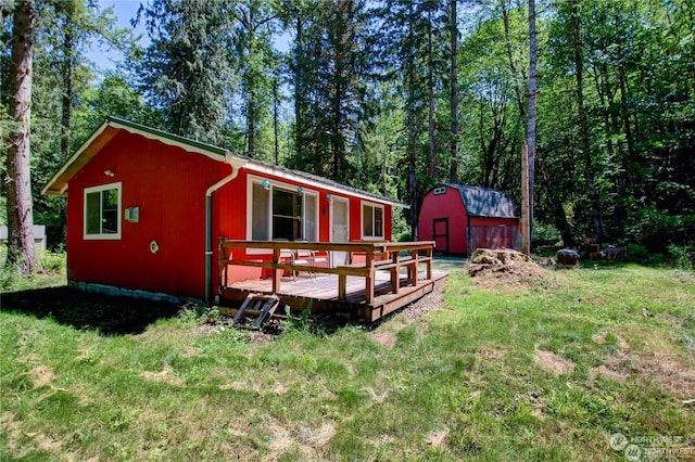 back of house with a wooden deck, a lawn, and a storage unit