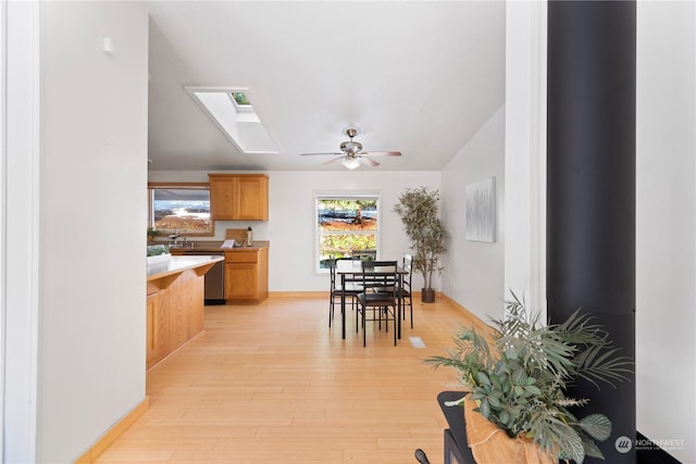 interior space with light hardwood / wood-style flooring, a skylight, and ceiling fan