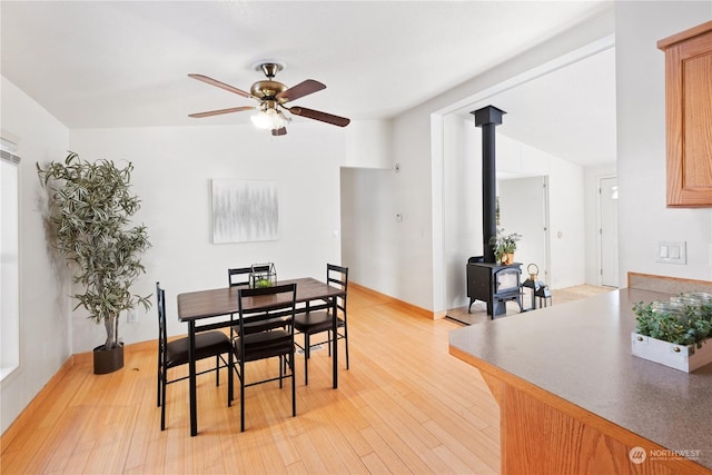 dining room with lofted ceiling, light hardwood / wood-style flooring, ceiling fan, and a wood stove